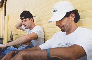 两名男子坐在米色混凝土墙旁