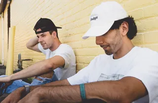 两名男子坐在米色混凝土墙旁