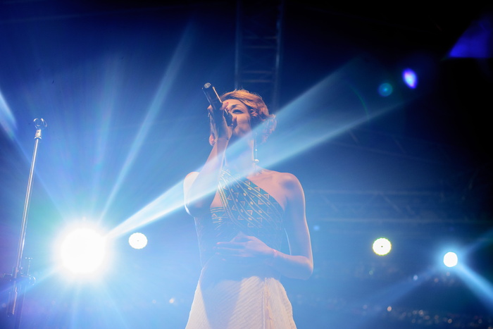 穿着黑色单肩上衣和米色裙子拿着麦克风的人