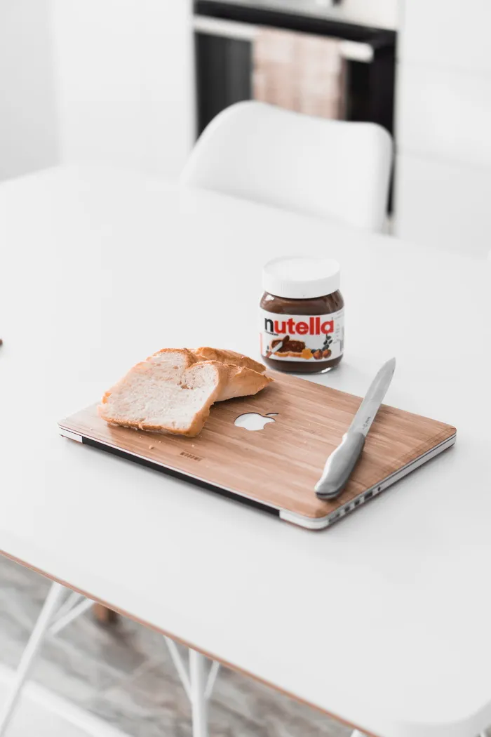 MacBook上的切片面包放在Nutella巧克力瓶旁边