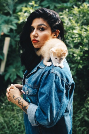 肩上扛着橙色塔比猫的站立女性