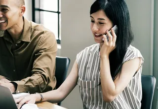 使用笔记本电脑时接听电话的女性