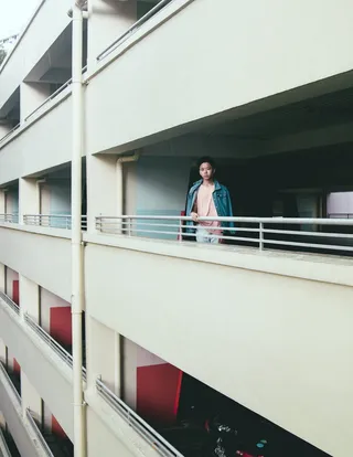 身穿粉红色衬衫的男子站在阳台附近