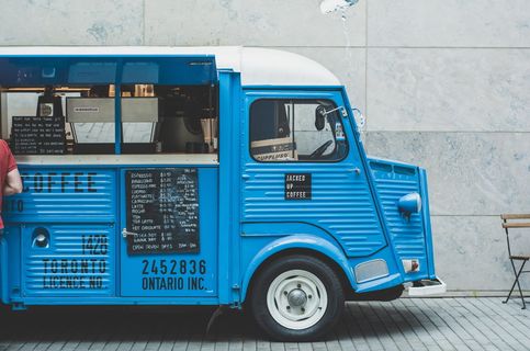 蓝色食品车，蓝色，白色，咖啡车，停车，水泥墙，白天，公共汽车