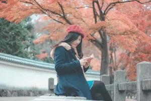 穿着蓝色派克夹克的女人坐在灰色混凝土长凳上看书