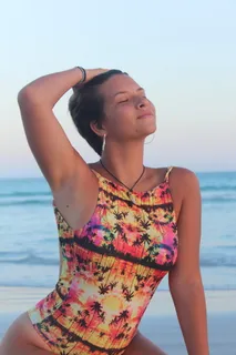 一名身穿五彩连体泳衣的女子闭着眼睛摆姿势的照片