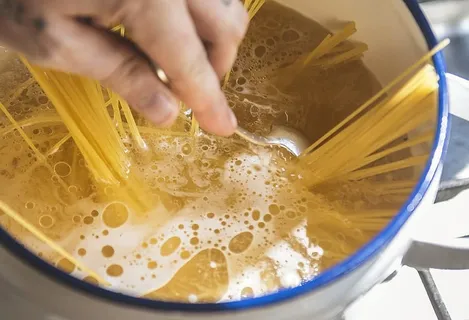 搅拌装满液体的砂锅菜时拿着不锈钢勺子的人 搅拌装满液体的砂锅菜时拿着不锈钢勺子的人