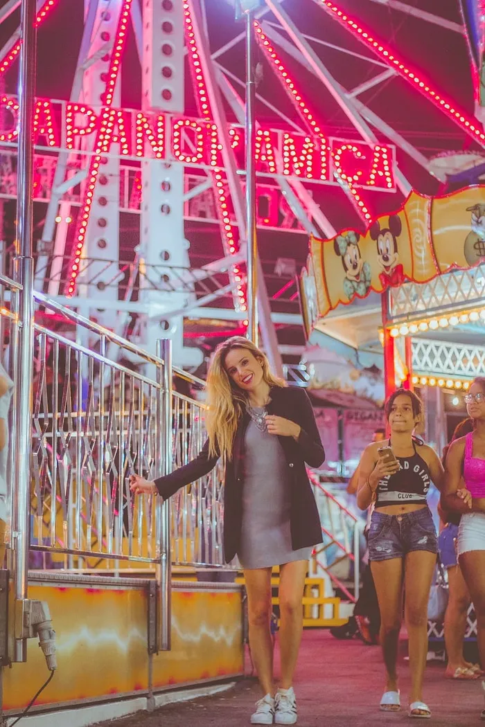 身穿黑色外套的女子站在摩天轮附近