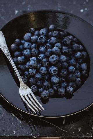 新鲜蓝莓放在黑色盘子里，搭配复古餐具
