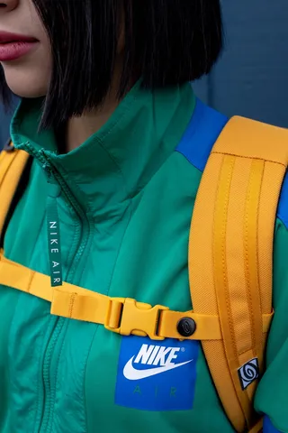 穿着绿色Nike Zip上衣和黄色背包的女士