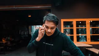 男子穿着黑色套头衫连帽衫使用智能手机