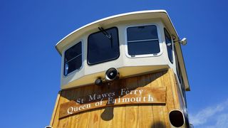 在晴朗的蓝天下，白色和棕色的圣马维斯渡轮是费茅斯船的女王