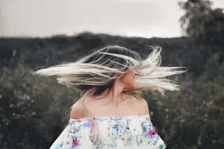 一位身着花卉连衣裙的女士做头发翻转的照片