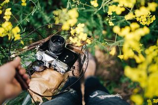 在盛开的油菜地里拿着老式相机的女人