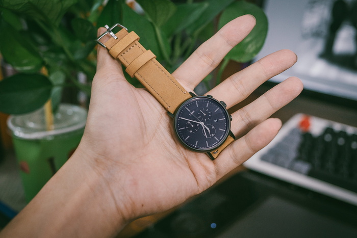 拿着棕色皮带黑色计时手表的人