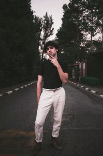 身穿黑色短袖的衬衫及白色长裤的男子站立