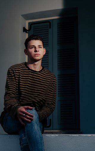 穿着条纹长袖衬衫的男子双腿交叉坐着的照片