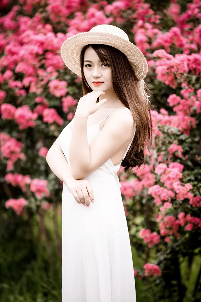 穿着裙子的女人站在粉红色的花旁边