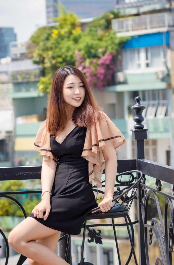 浅焦照片：一名身穿黑色连衣裙的女子坐在酒吧的椅子上