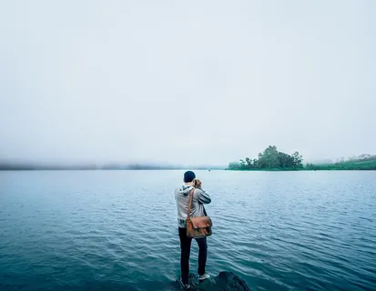 白天,身穿灰色连帽衫的男子站在水体附近的岩层上 白天,身穿灰色连帽衫的男子站在水体附近的岩层上