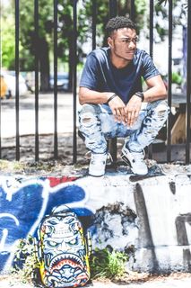 白天，身穿黑色圆领 T 恤的男子蹲在黑色金属栅栏旁