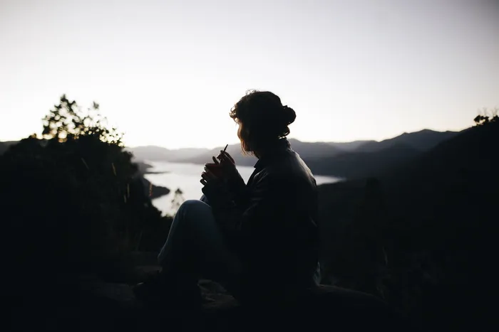 坐在植物旁边的人的剪影横过大片水域