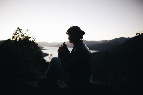 坐在植物旁边的人的剪影横过大片水域