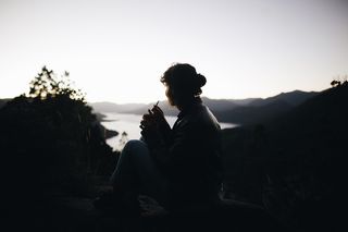 坐在植物旁边的人的剪影横过大片水域