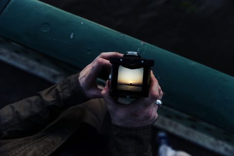 手持日落显示摄像头的人