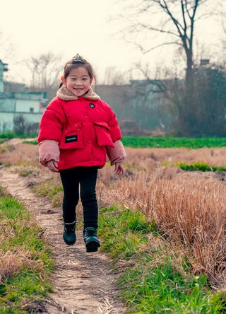 女孩白天在绿草旁的小路上跑步