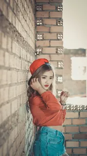 棕色混凝土砖旁穿着橙色上衣的女孩 棕色混凝土砖旁穿着橙色上衣的女孩