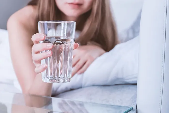 早上在床上拿着一杯水的女人的特写镜头