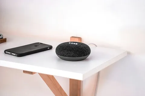 黑色iPhone放在圆形便携式扬声器旁边的木桌上 黑色iPhone放在圆形便携式扬声器旁边的木桌上