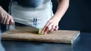 在砧板上切绿色蔬菜的人 在砧板上切绿色蔬菜的人