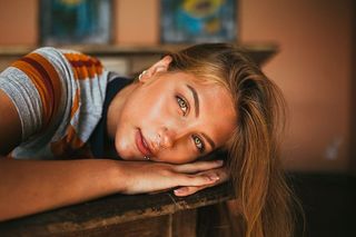 一张女人的脸靠在棕色表面的特写照片