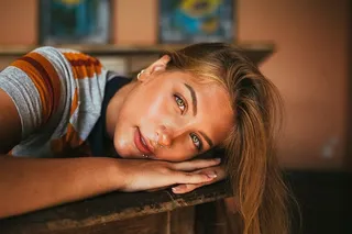 一张女人的脸靠在棕色表面的特写照片