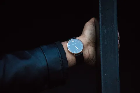 戴着带表带的圆形模拟手表的人