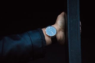 戴着带表带的圆形模拟手表的人