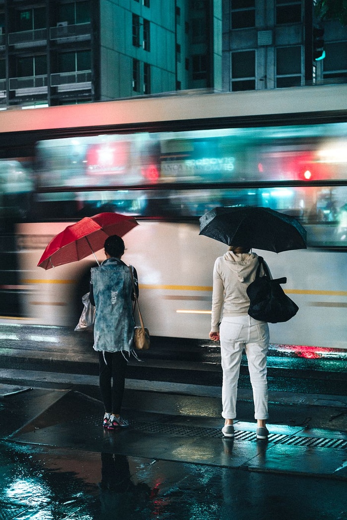 夜间，妇女站在户外打开的雨伞下