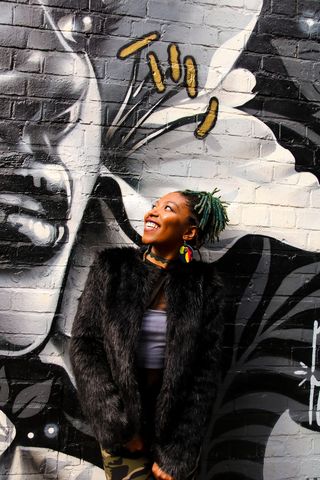 身穿黑色皮衣的女子站在涂鸦墙上的照片