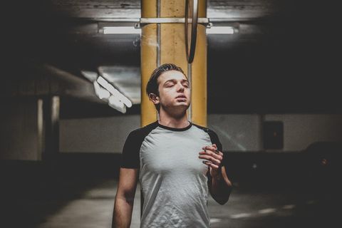 身穿灰色和黑色连肩T恤的男子站在橙色立柱附近