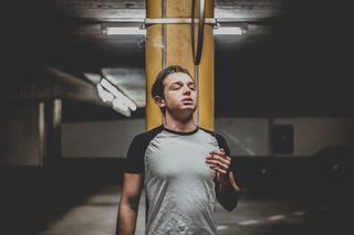 身穿灰色和黑色连肩T恤的男子站在橙色立柱附近