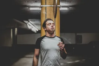 身穿灰色和黑色连肩T恤的男子站在橙色立柱附近