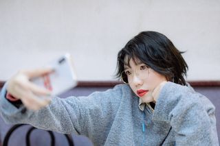 穿着灰色连帽衫拍照的女子