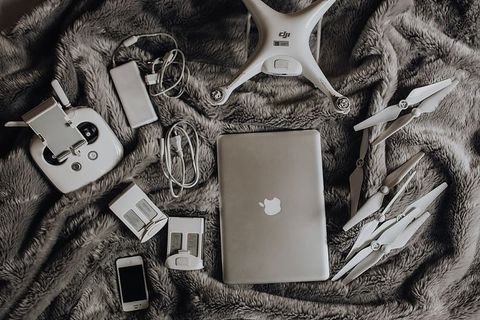 无人机、笔记本电脑和配件躺在床上准备旅行