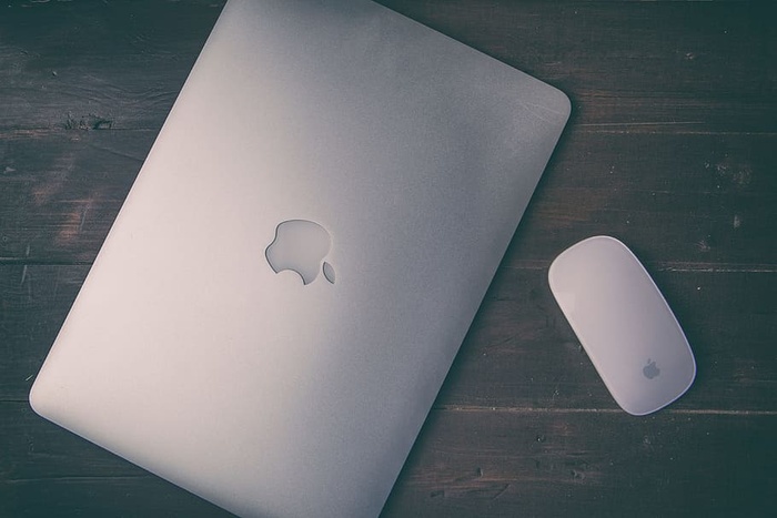 苹果Macbook Pro视网膜和坐在木桌上的神奇鼠标的模糊头顶照片