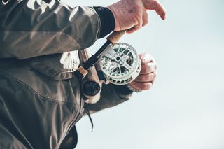 拿着棕色和白色钓鱼竿的人