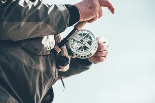 拿着棕色和白色钓鱼竿的人