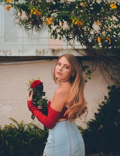 身穿红色露肩上衣手持鲜花的女子