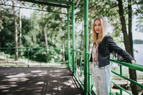 穿着黑色夹克和绿色扶手撕破牛仔裤的金发女人 穿着黑色夹克和绿色扶手撕破牛仔裤的金发女人